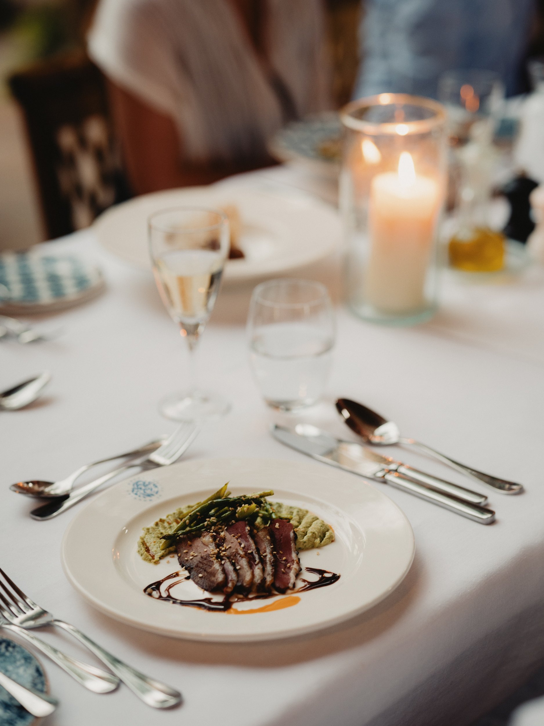 Dinner laid by candlelight, a plated course on white linen