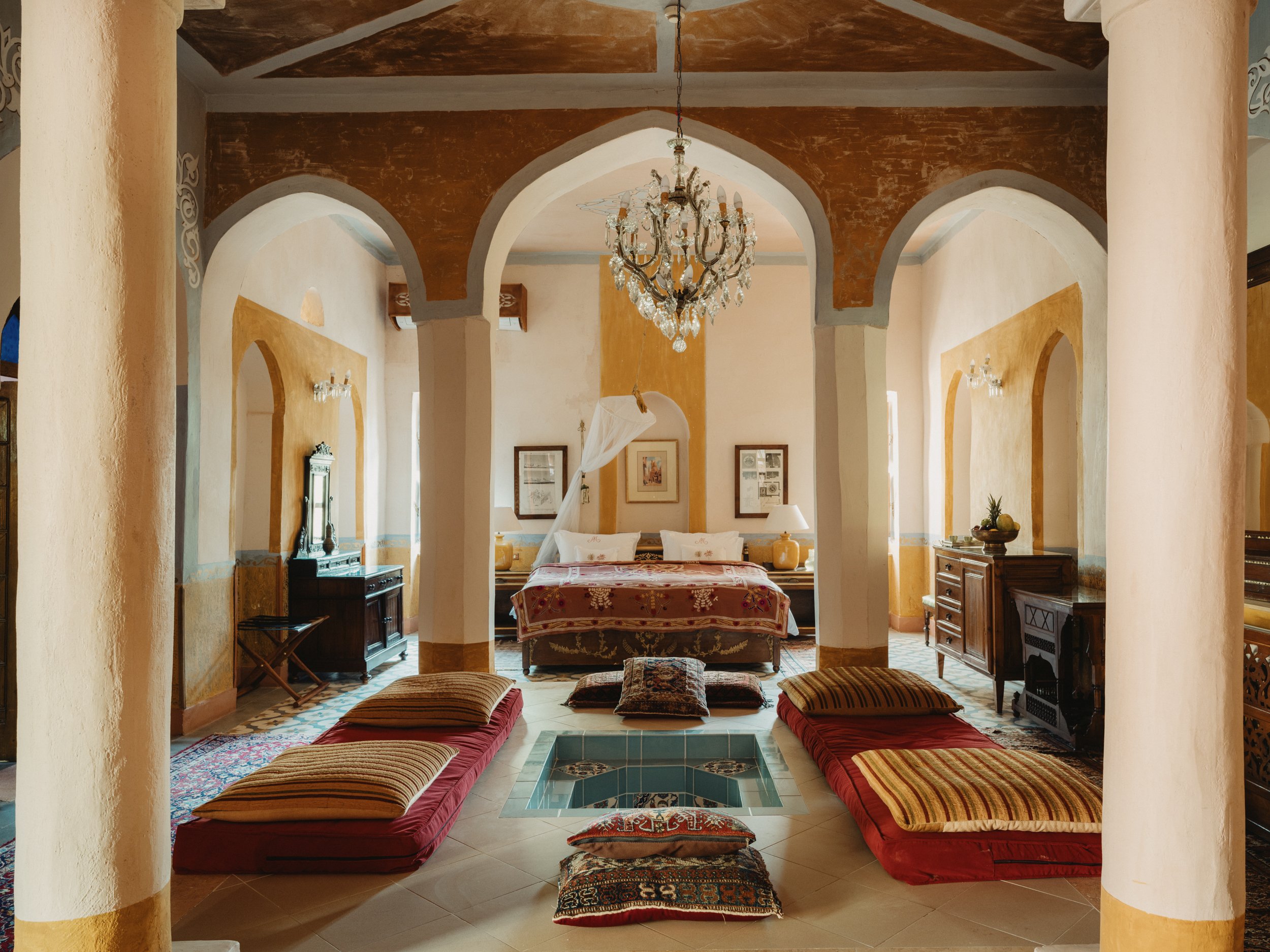 A vaulted suite with arches, a chandelier and low cushioned seating