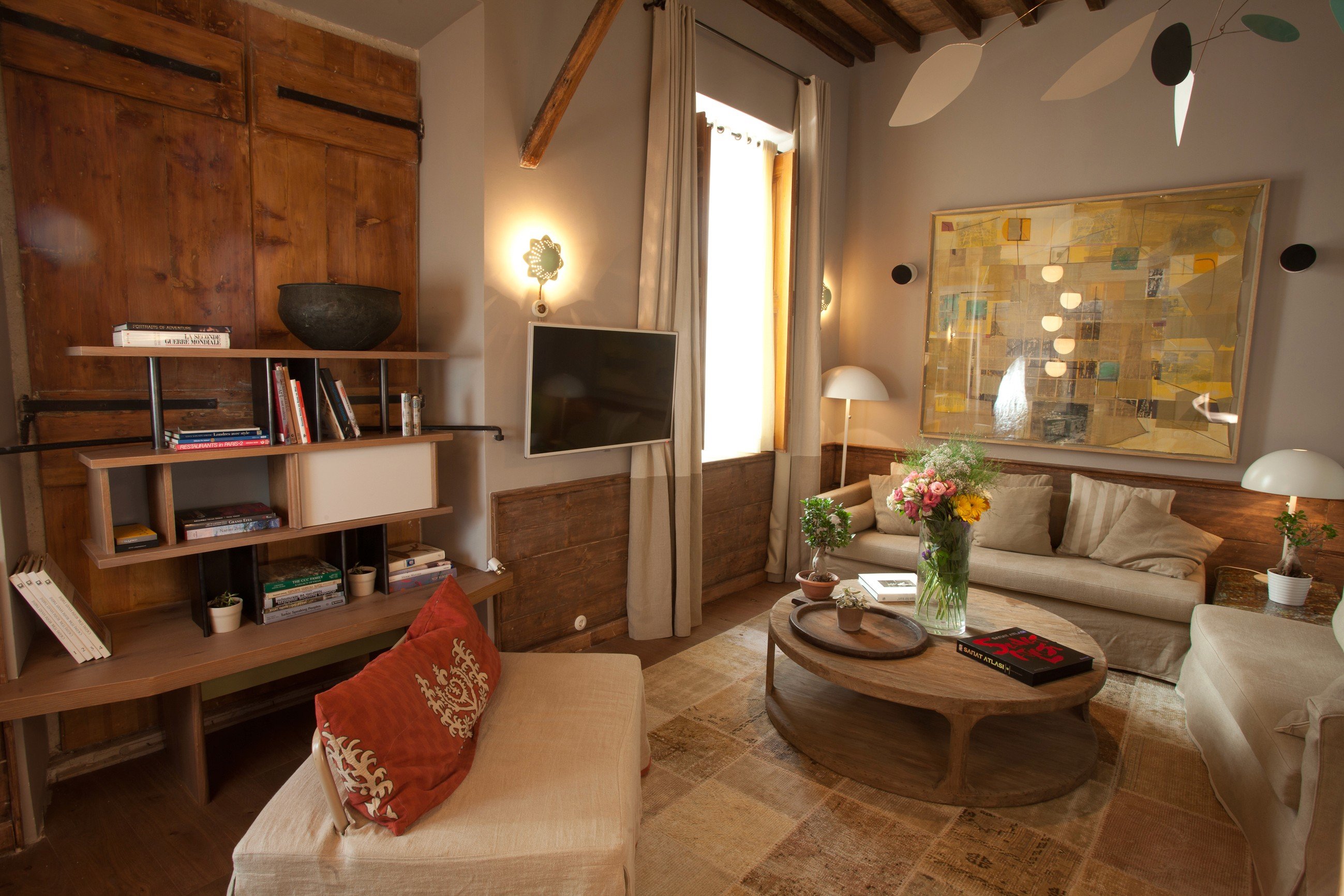 A suite sitting room under a beamed ceiling with a large canvas above the sofa
