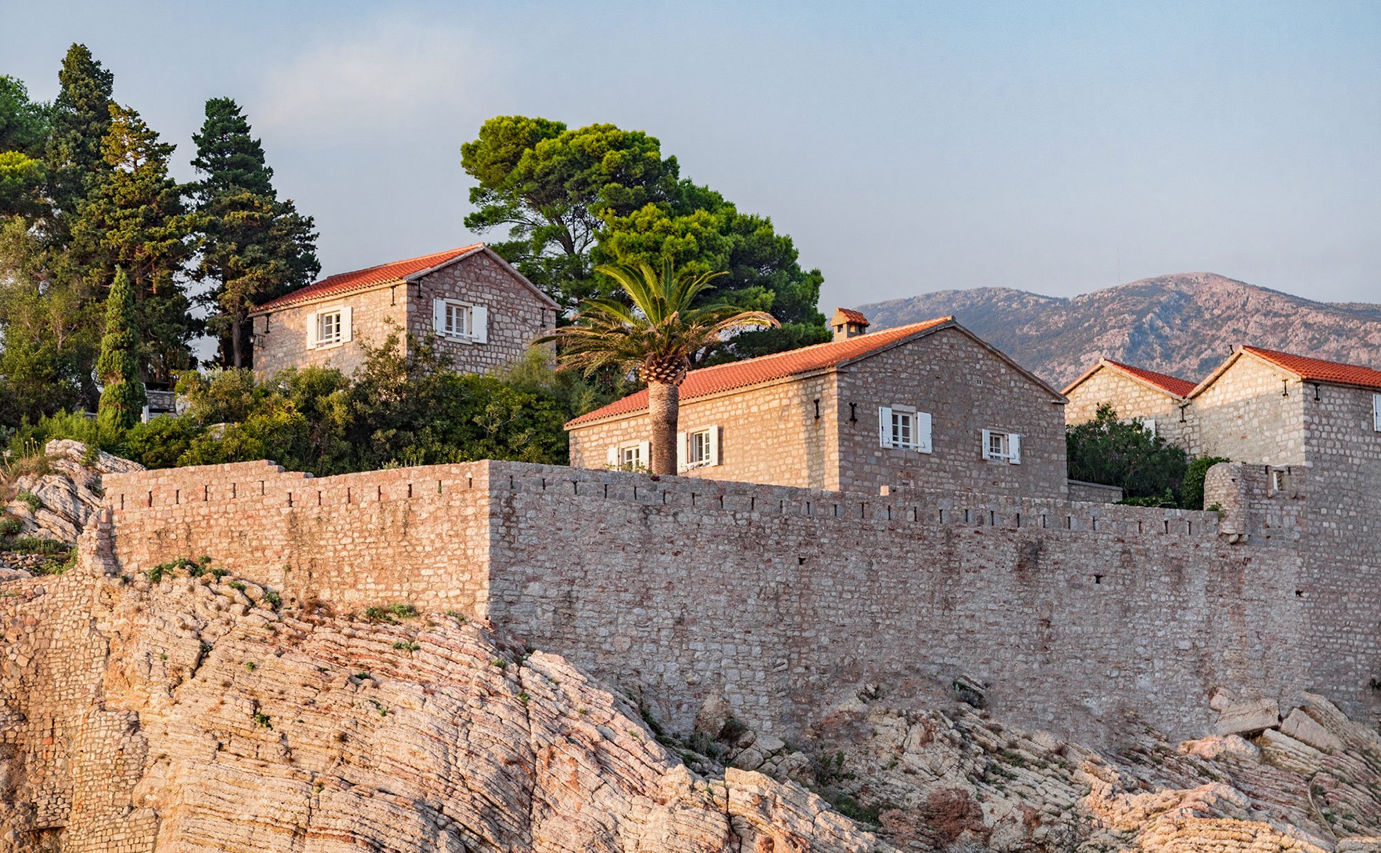 Restored stone cottages rising behind the island's sea walls, a palm and pines above