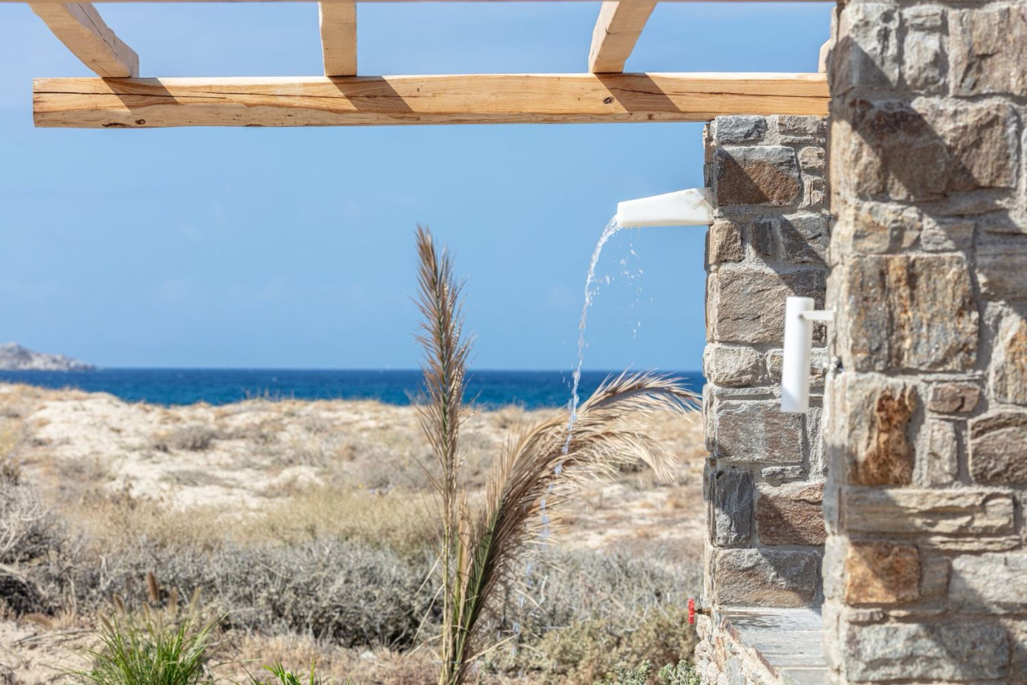 A stone pergola framing the sea and the dune grasses