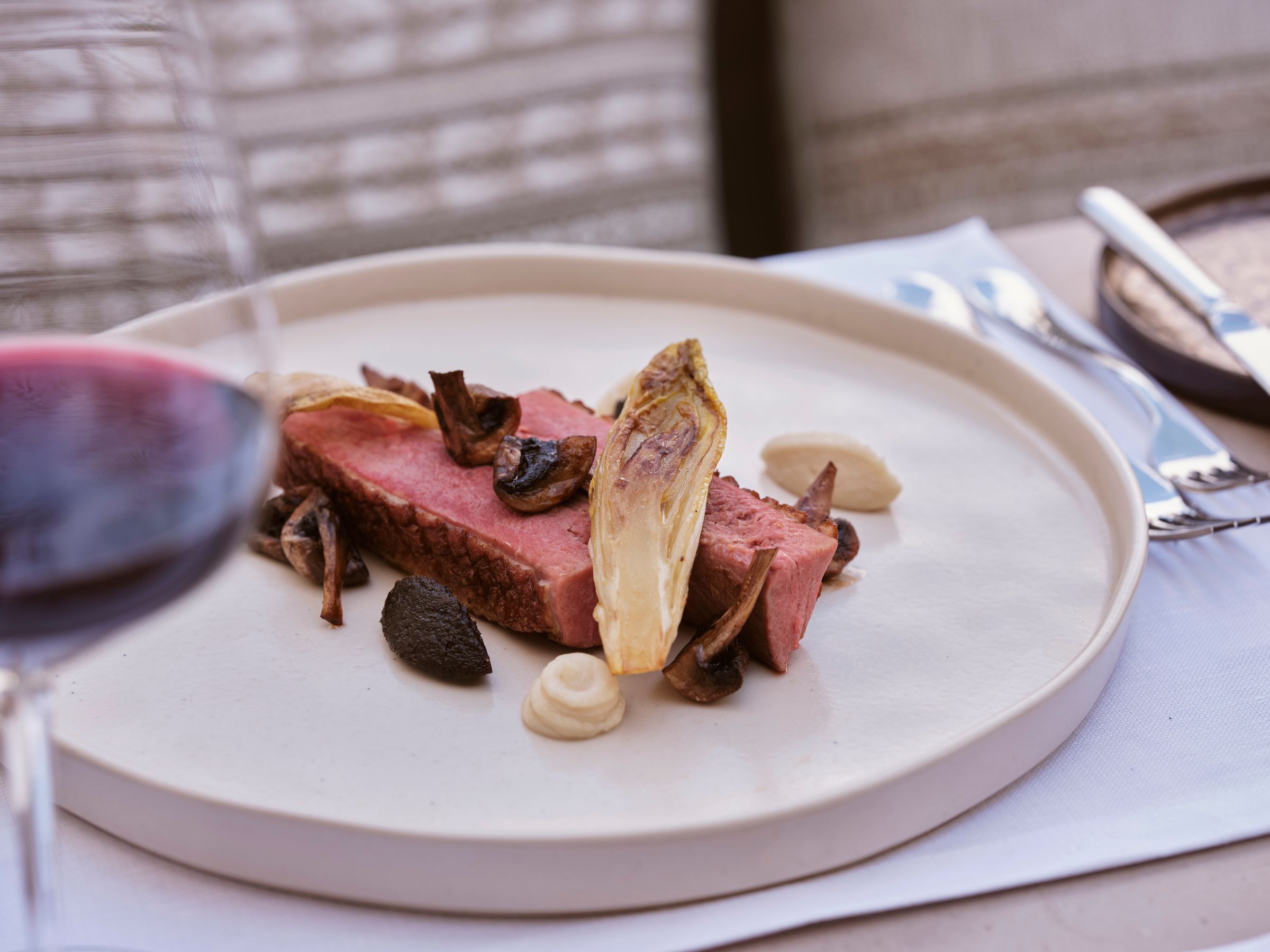 A plated course at the courtyard restaurant with a glass of red wine