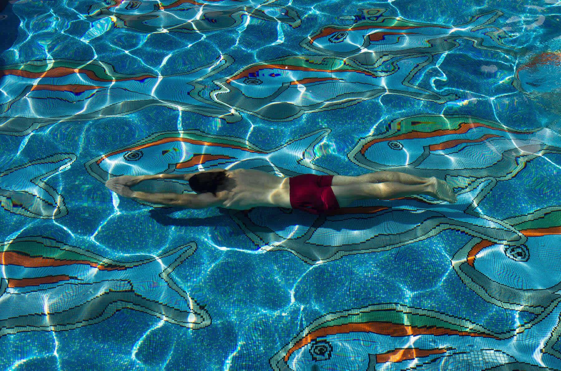 A swimmer over the mosaic floor of the pool