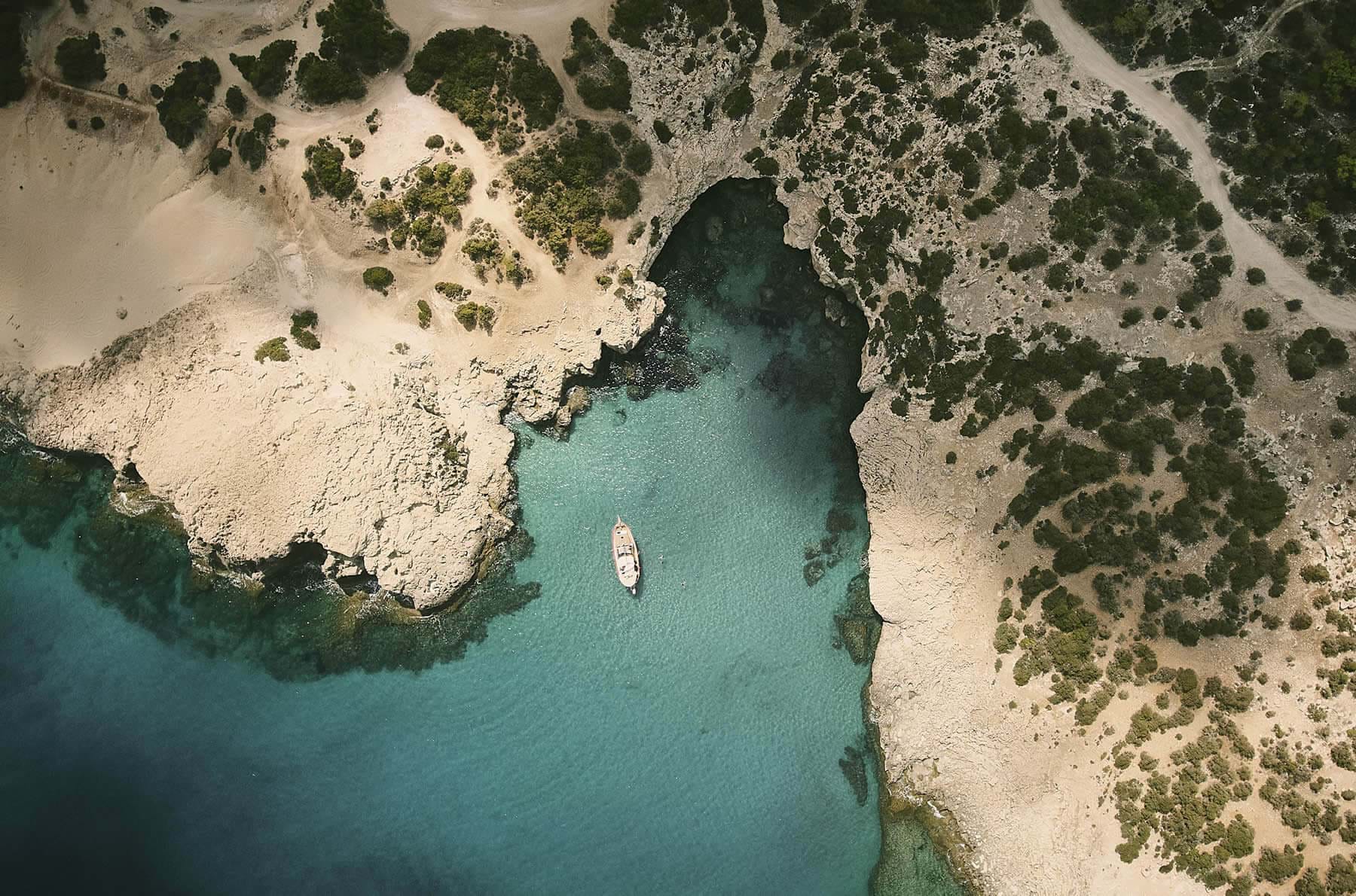 A boat at anchor in a rocky cove on the wild Akamas coast
