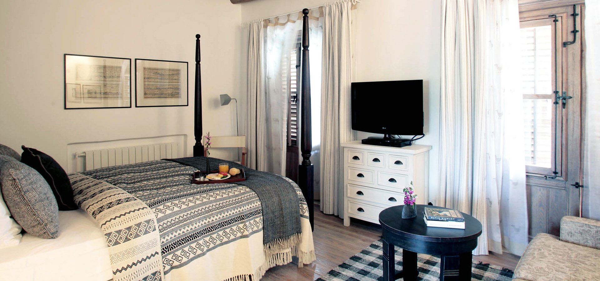 A room with a four-poster bed and shuttered windows