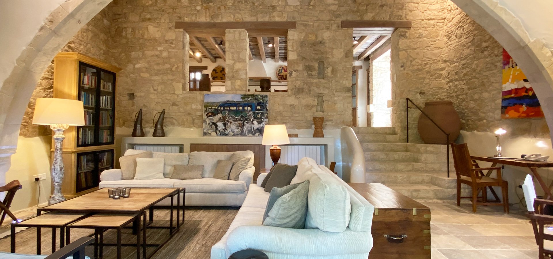 The lounge beneath a stone arch, with a library and an open fire