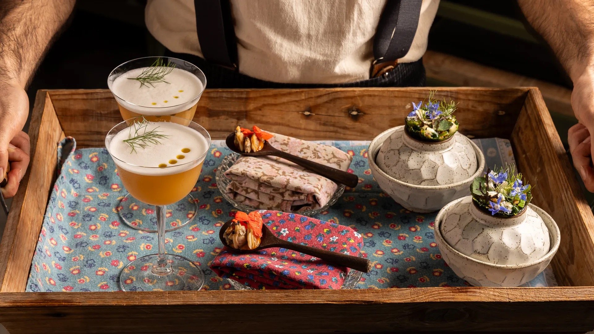 A wooden tray of aperitifs and garden amuse-bouche, herbs and edible flowers from the hotel's beds