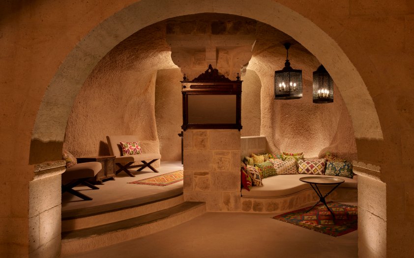 A vaulted cave sitting room cut from the rock, with kilims and lanterns
