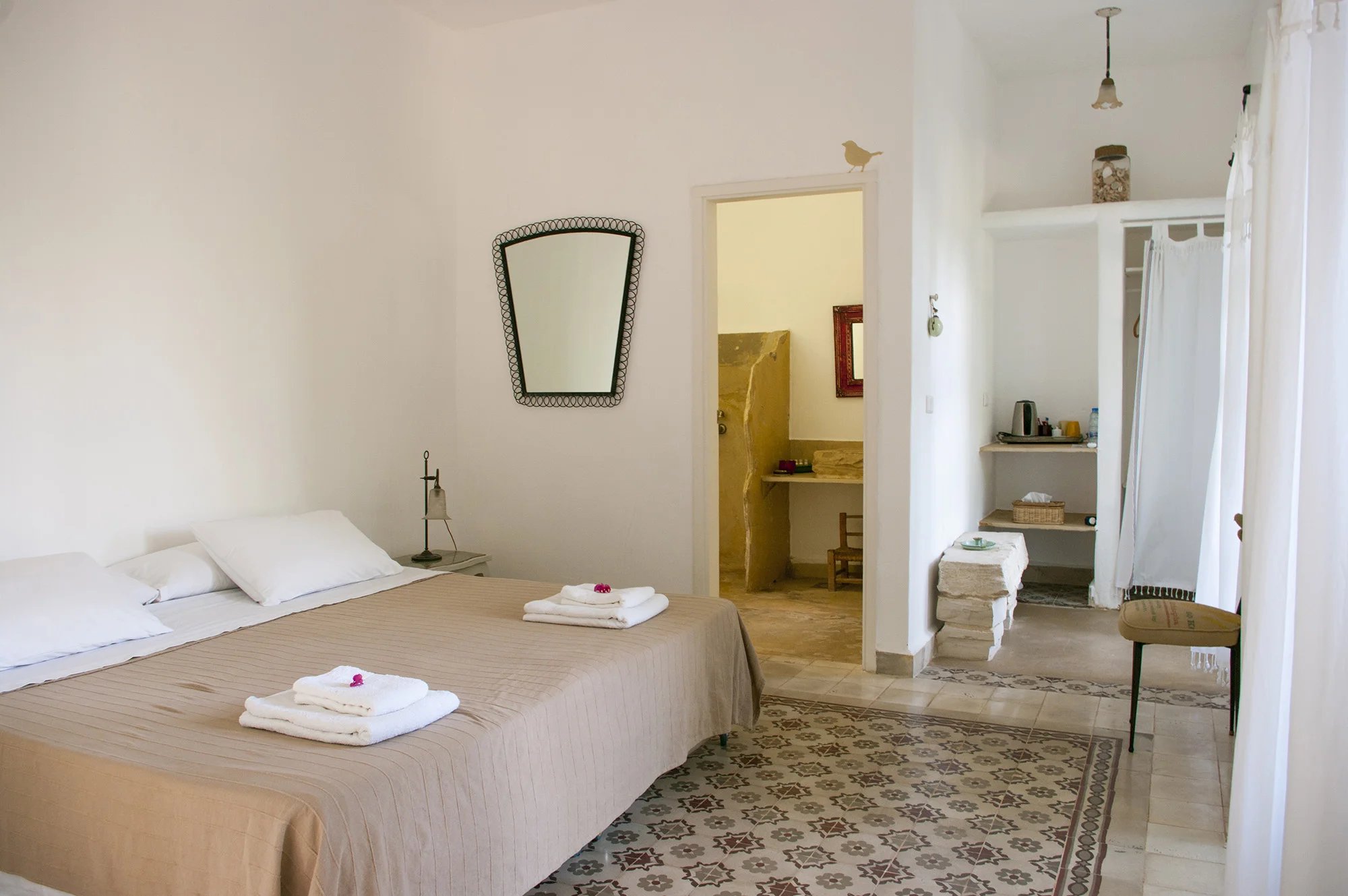 A bedroom with a patterned cement-tile floor and a salvaged mirror