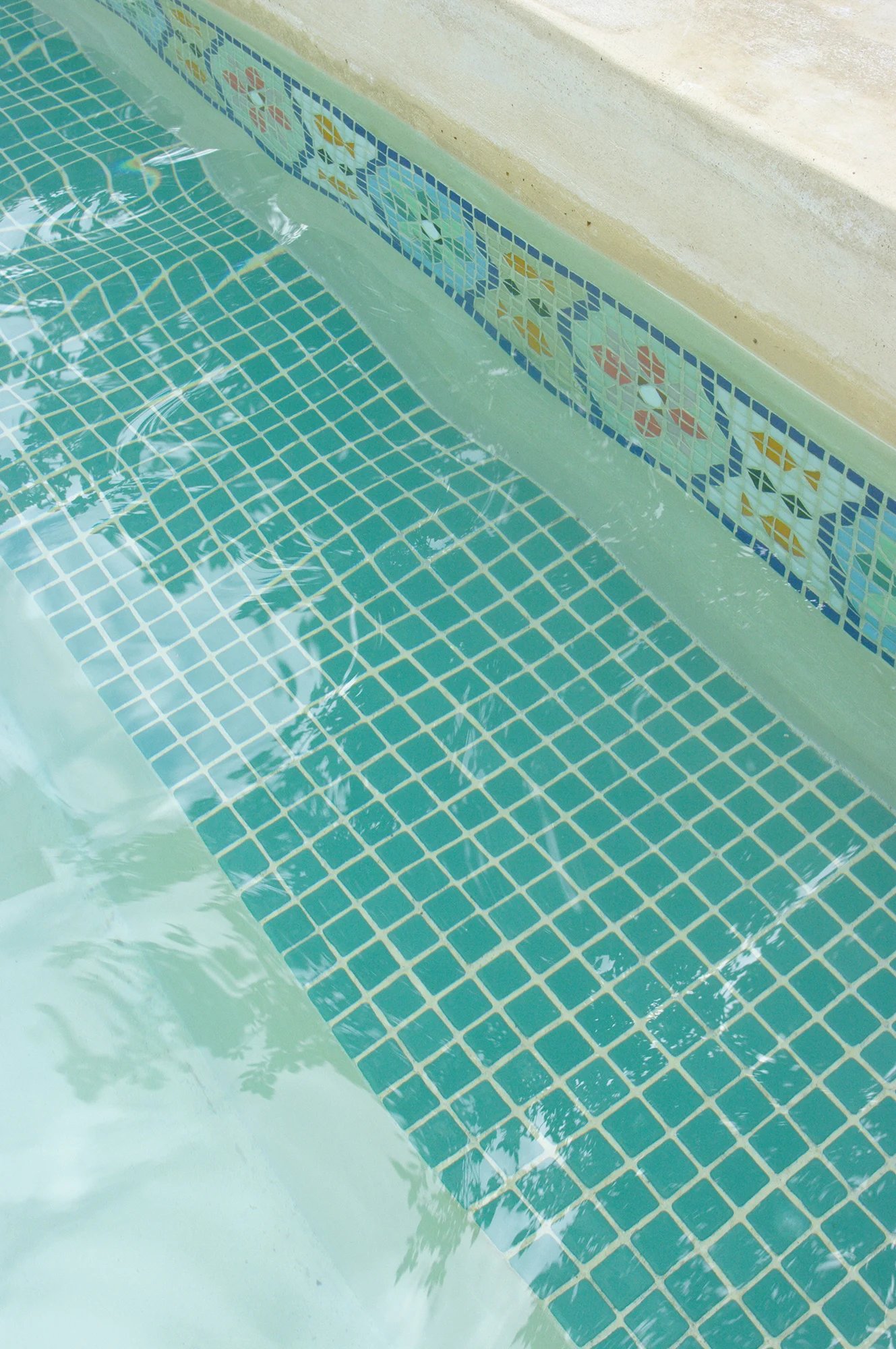 The green mosaic tiles of the plunge pool in the terrace corner