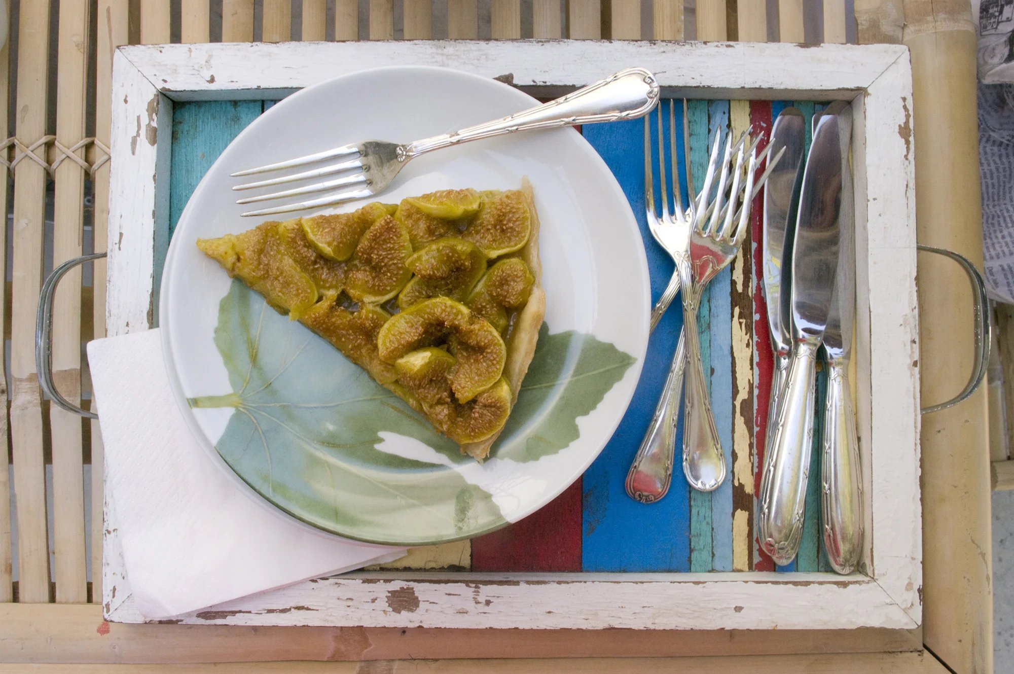 A slice of fig tart on a painted, salvaged wooden tray