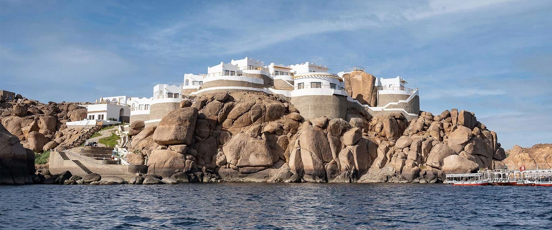 BenBen by Dhara seen from the Nile by day, its white rooms rising over the brown granite boulders of Heissa island with feluccas moored alongside