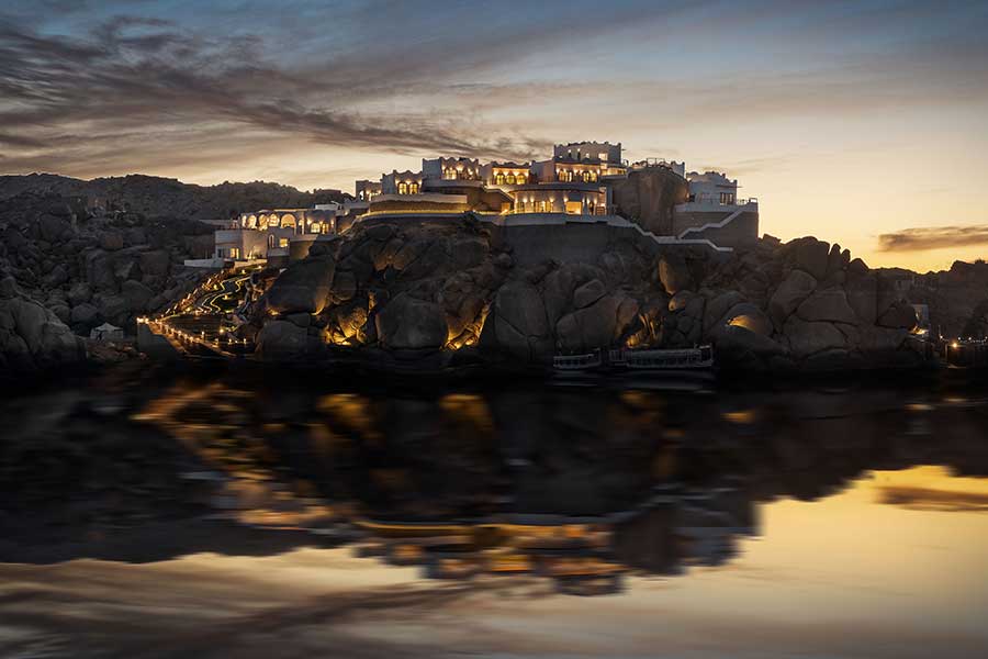BenBen lit at dusk on its granite island, mirrored in the still Nile