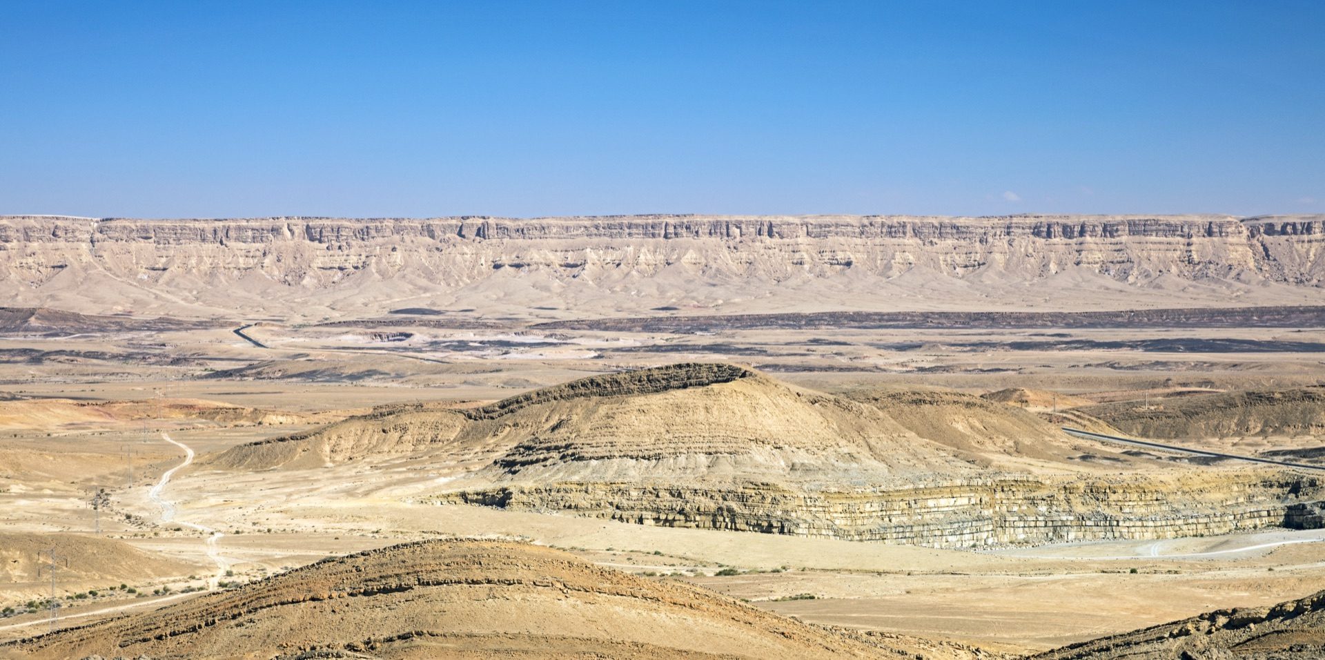 The layered cliffs and open floor of Makhtesh Ramon seen from the rim at Mitzpe Ramon, the erosion crater running out to the far wall