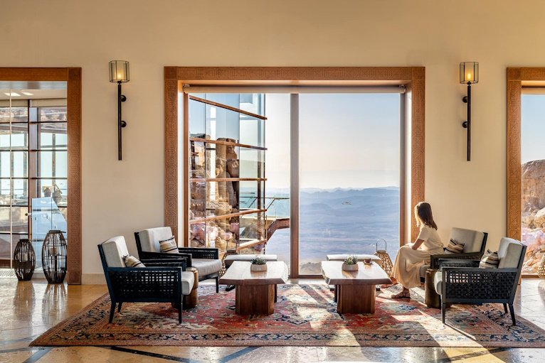 A suite's seating area opening through a tall window to the desert