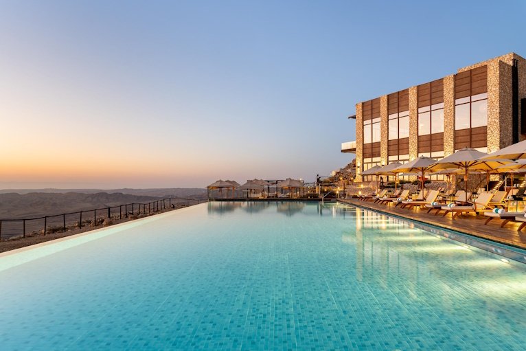 The long infinity pool and stone terrace above the crater at dusk