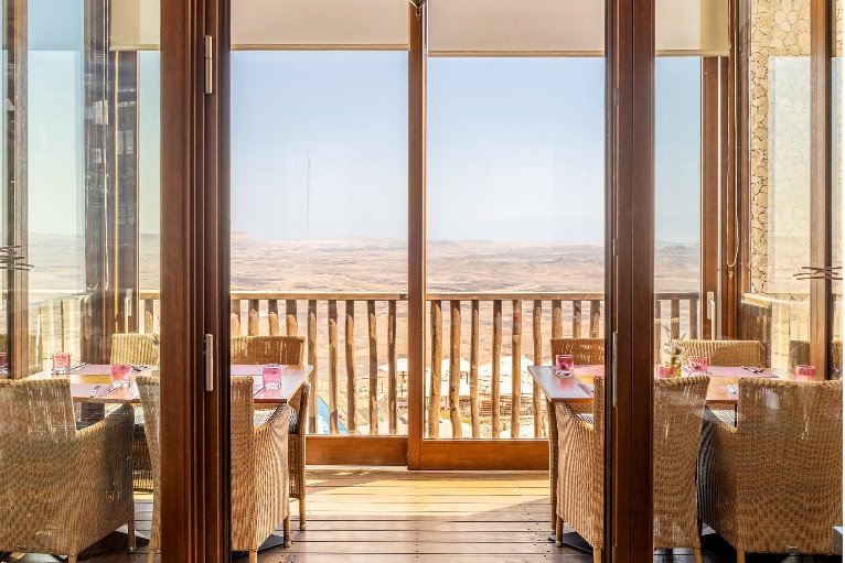 A private balcony set for dinner above the open desert