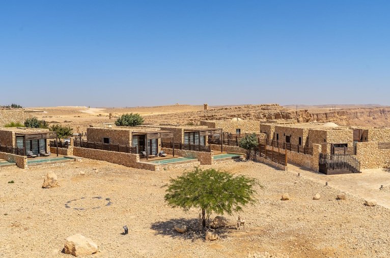 Villas and a lone acacia tree in the open Negev desert