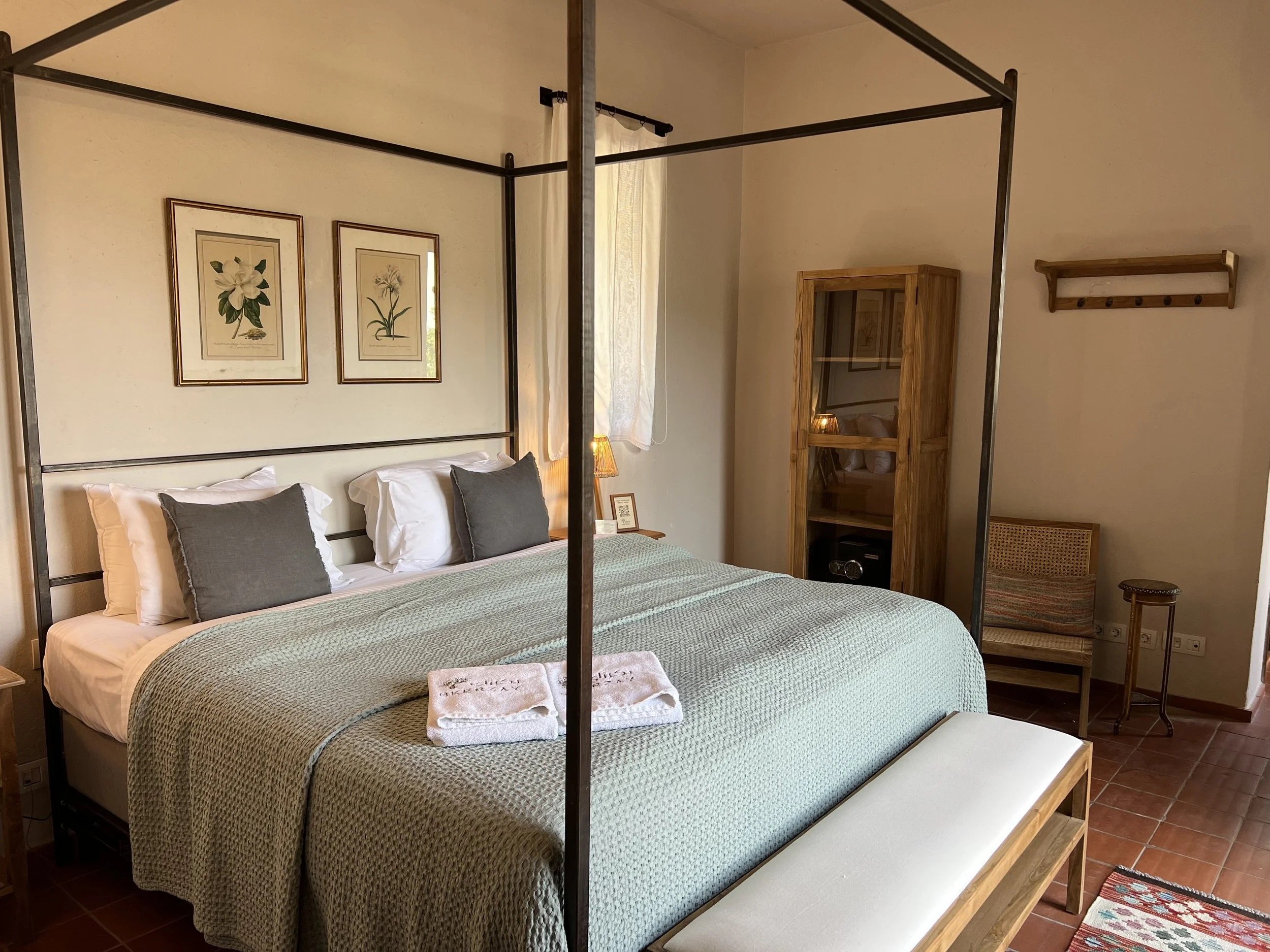 A room with a four-poster bed and botanical prints