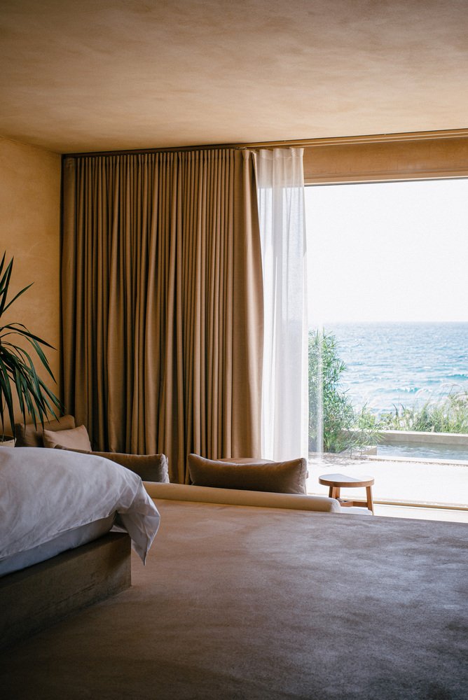 A suite with a low bed and sliding doors to the sea