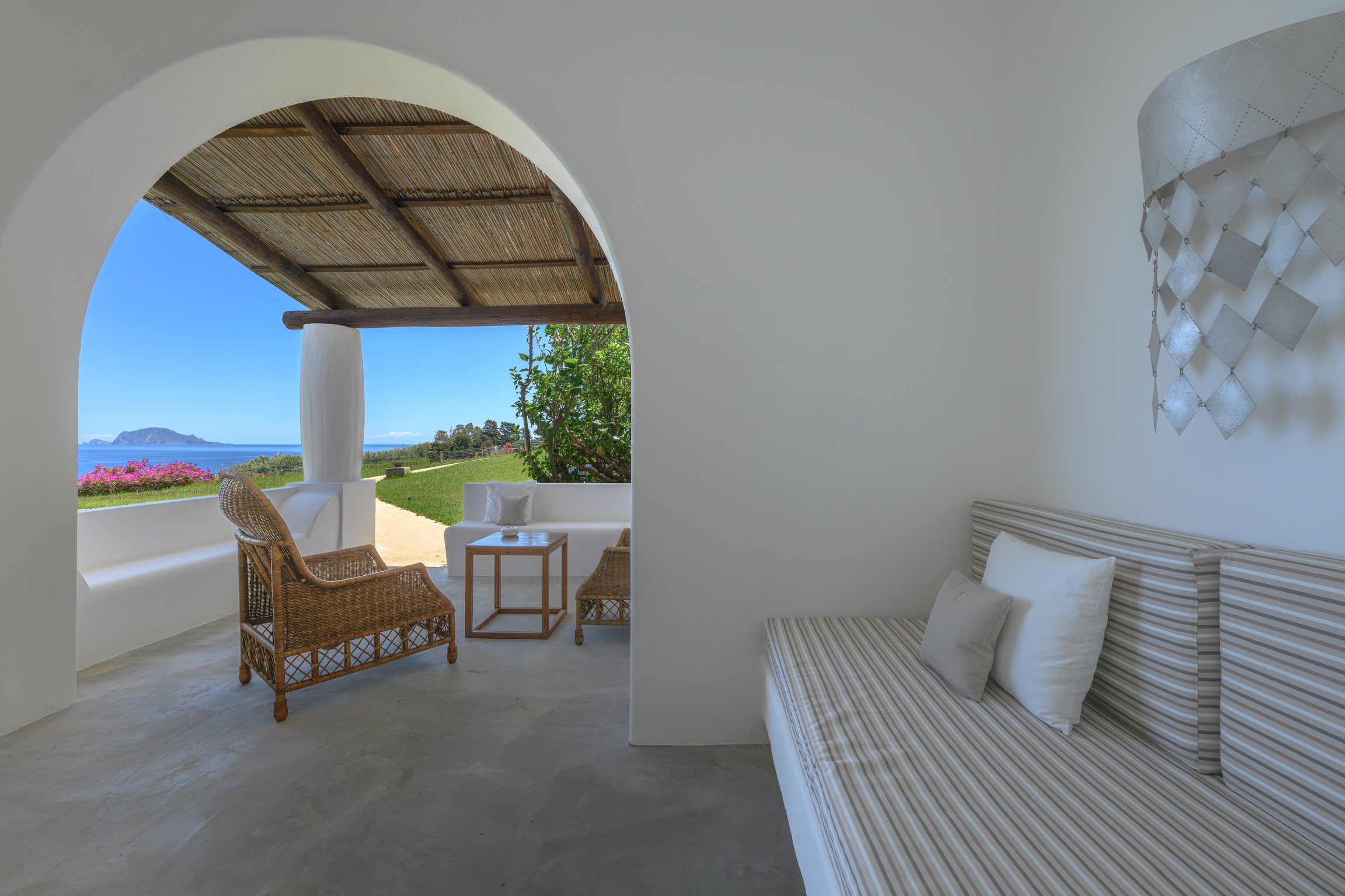 A room opening through an arch onto a private terrace and the sea