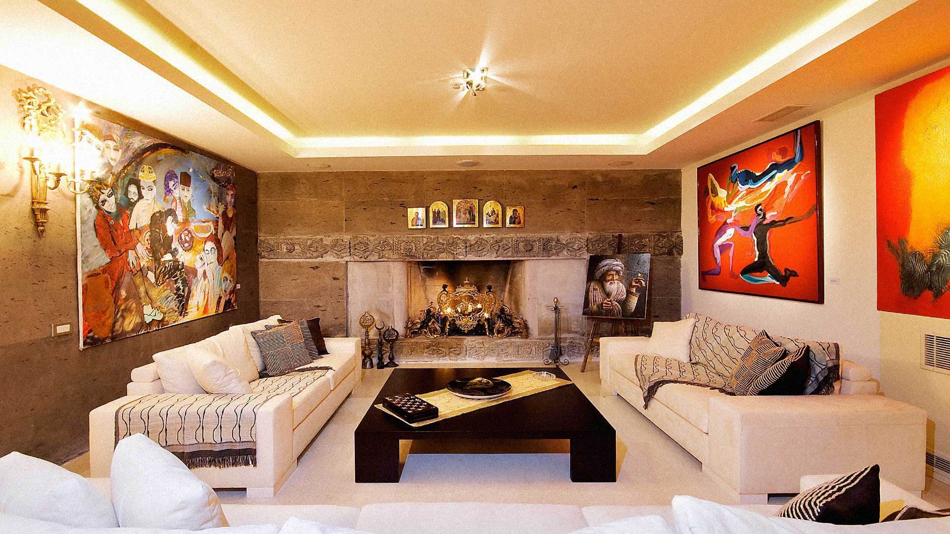 The garden salon hung with paintings from the family's collection, a stone fireplace at its centre