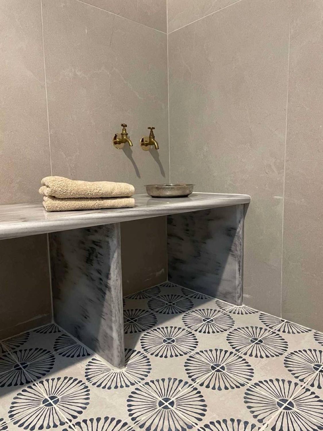 The bathroom, brass taps over a marble bench and patterned cement tiles