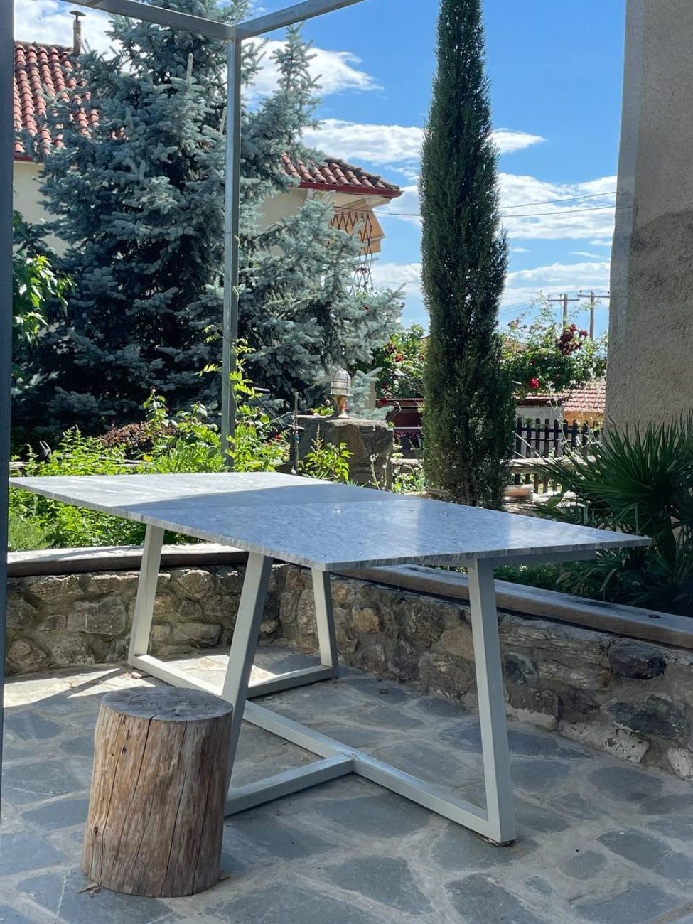 A marble-topped table on the terrace, looking out to the garden and a cypress
