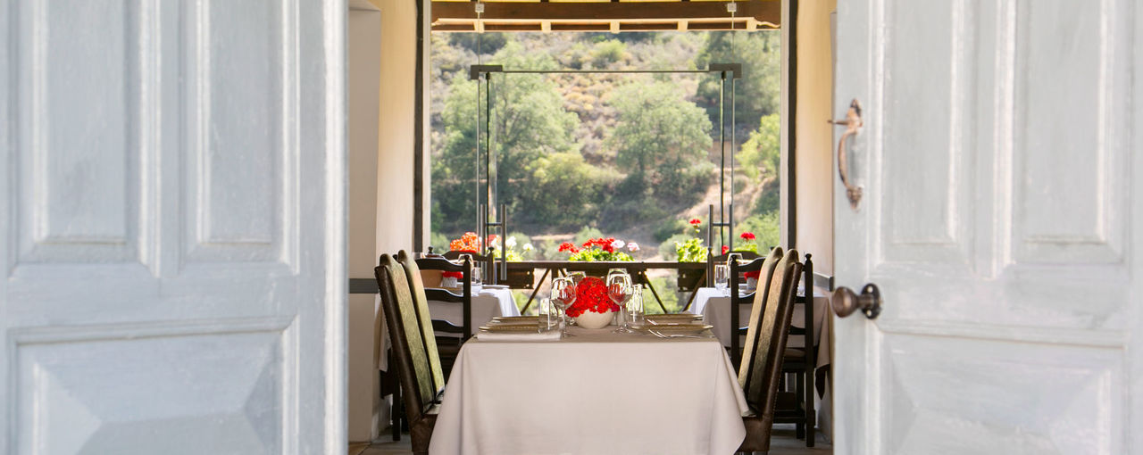A laid table framed by the white doors of a village house, the valley beyond