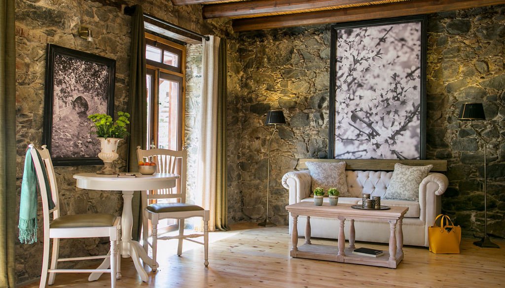 A stone-walled sitting room with timber ceiling and antique furniture