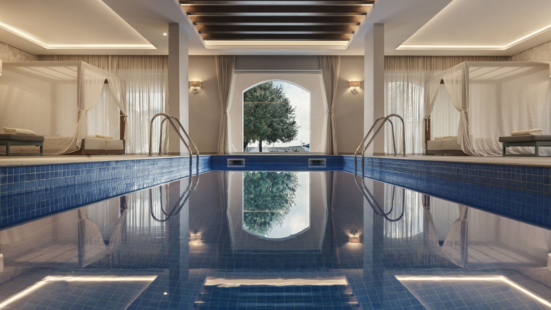 The indoor pool at the Chedi spa, an arched window framing a tree at the far end