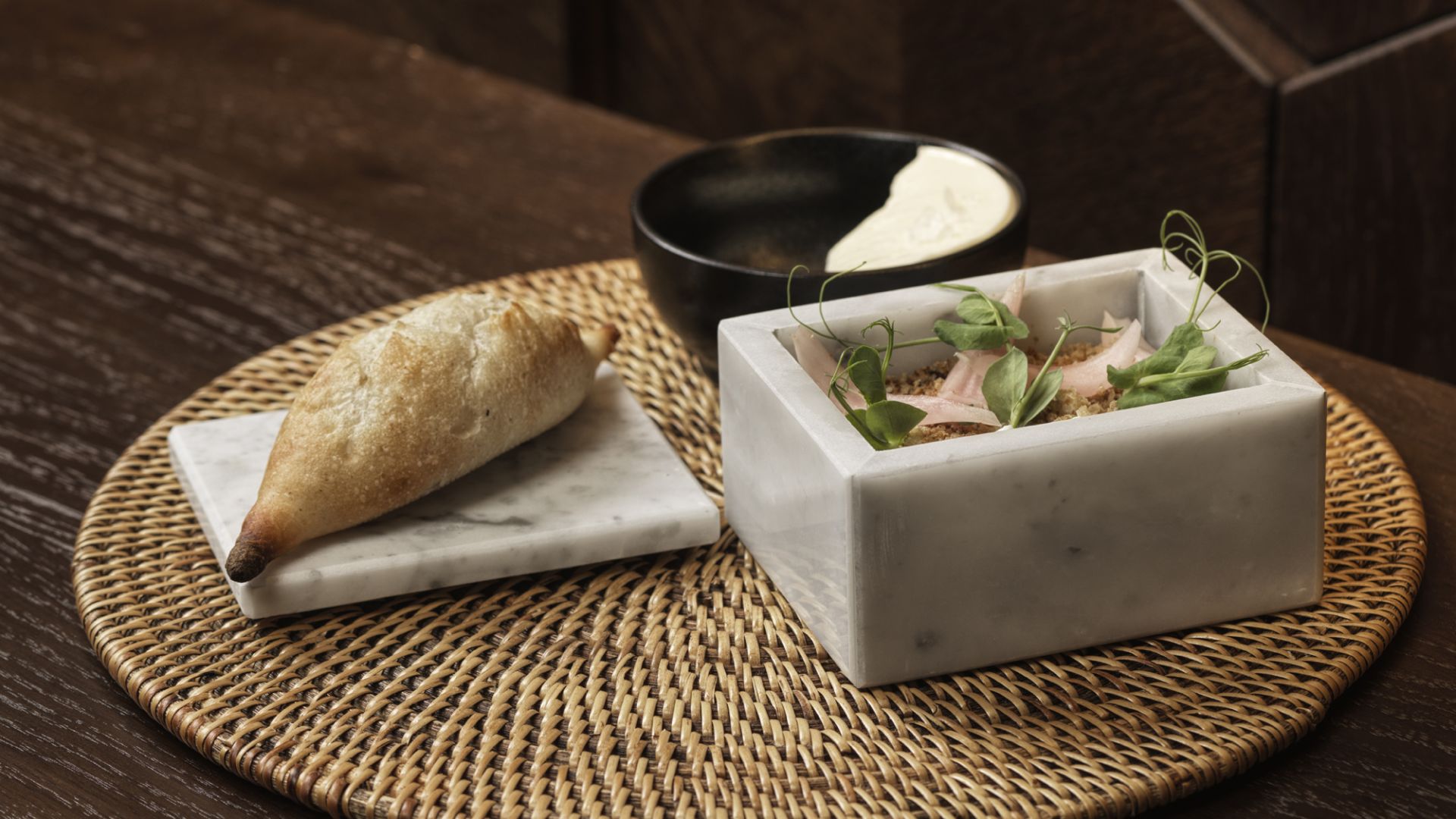 A plated dish served in a marble bowl with bread alongside