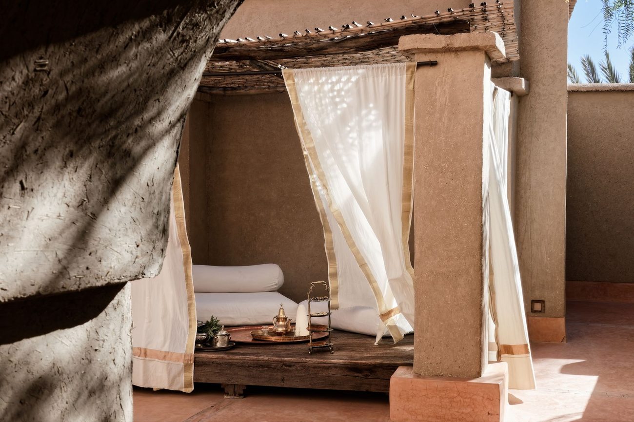 A rooftop daybed with white curtains in the morning light