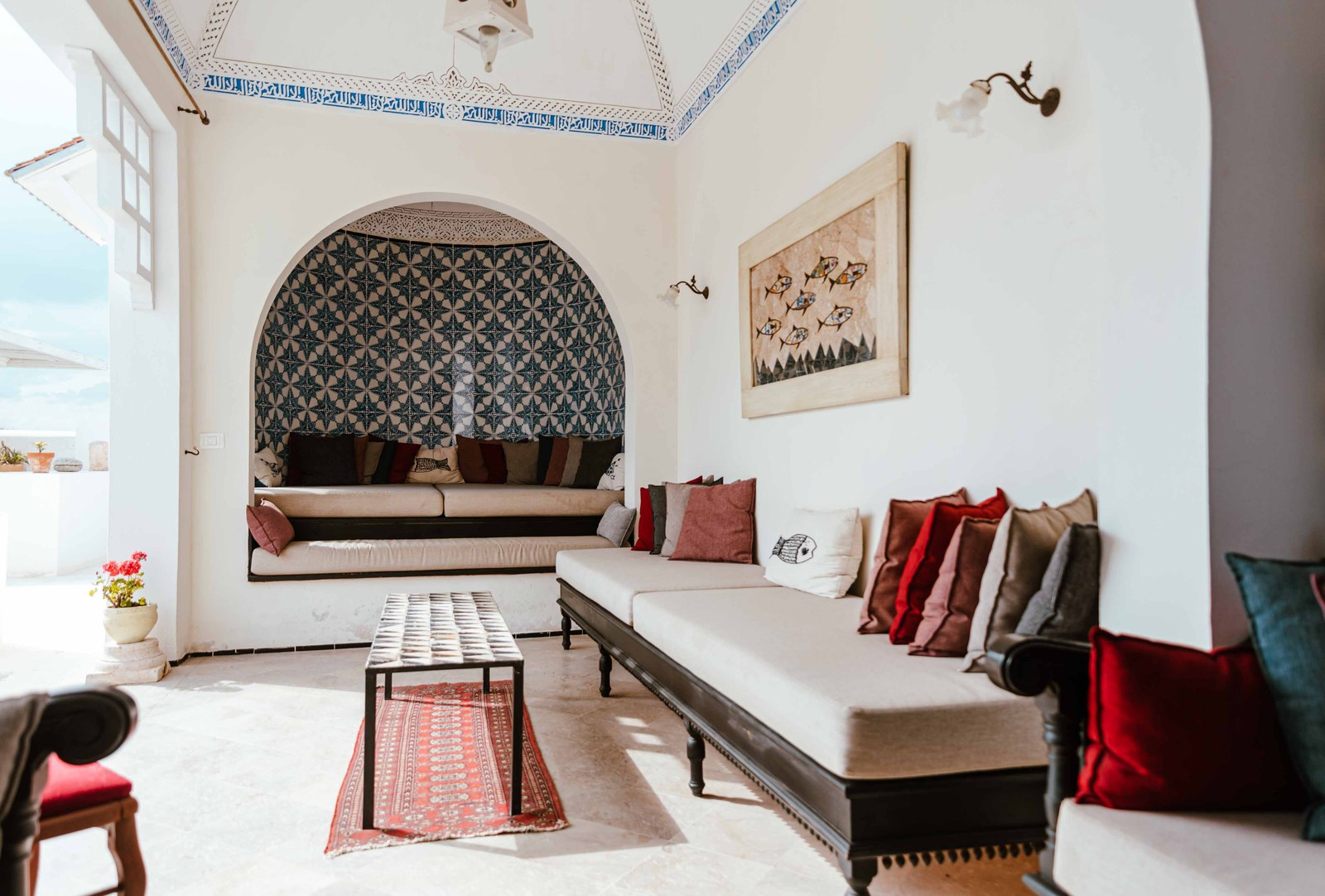 A tiled niche and banquette laid with red cushions in a Kahia room