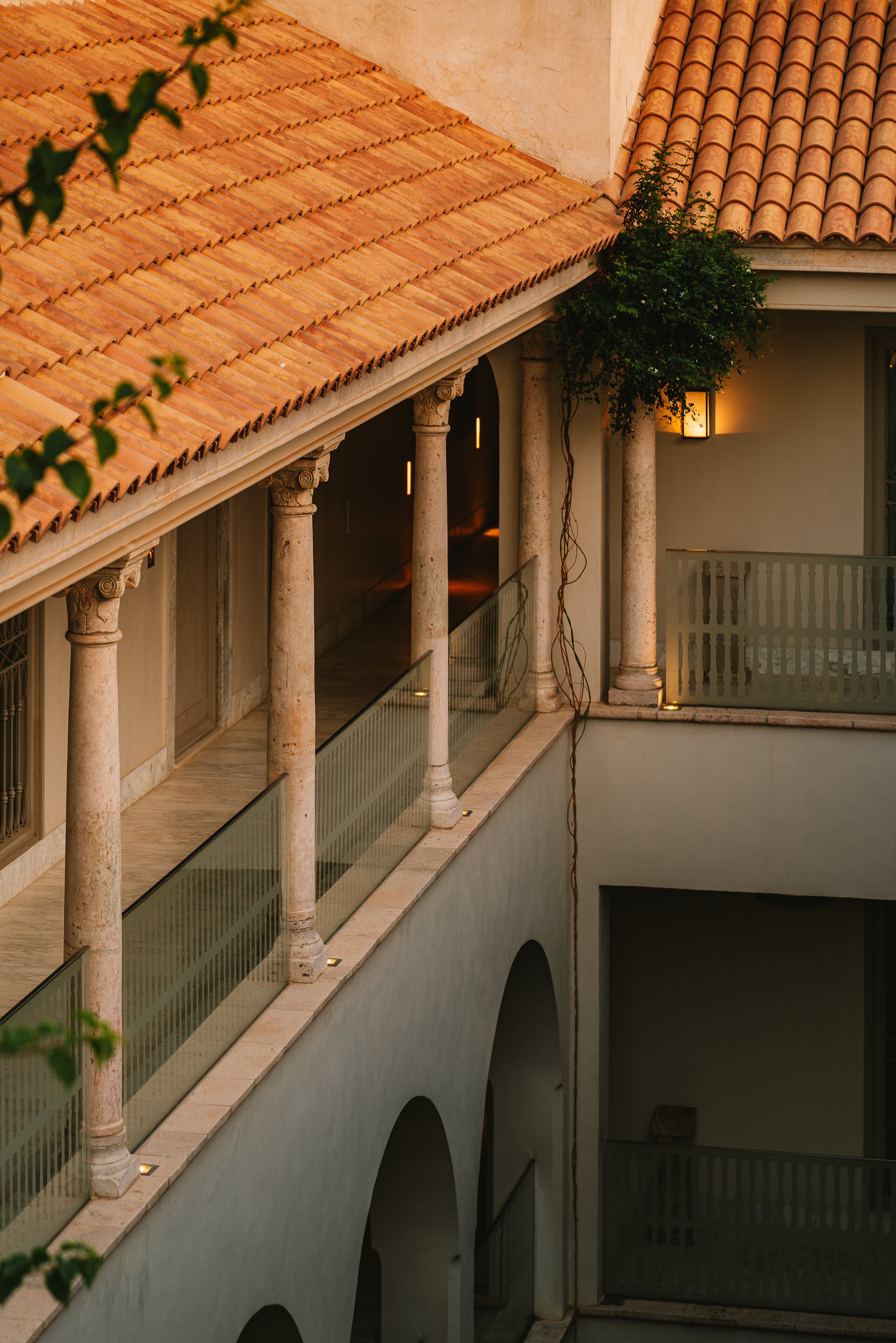 The colonnaded courtyard at dusk, a terracotta roof above the arcades