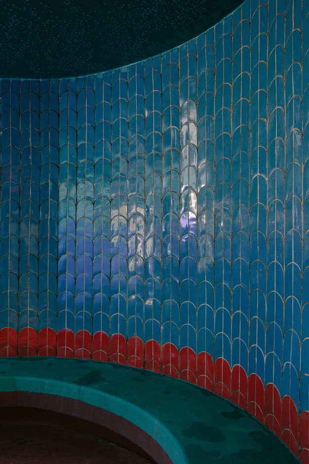 A pool wall clad in blue fish-scale tiles
