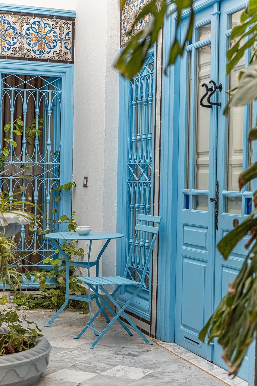 A courtyard corner with a blue door and a small café table