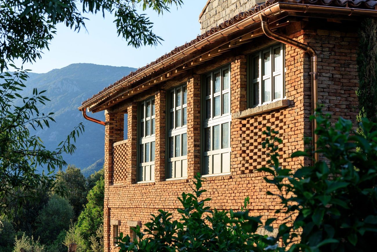 A restored house of dressed stone and brick against the wooded hills