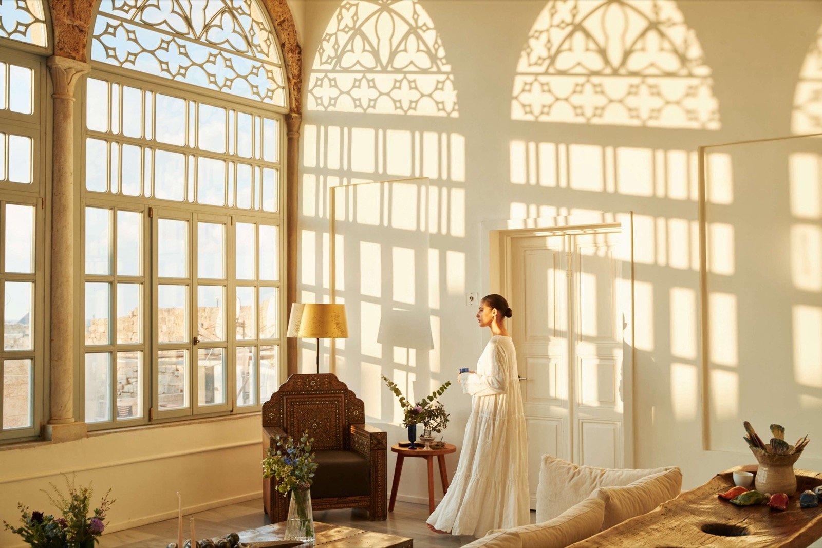 A suite with tall arched windows and carved stone latticework filtering the light