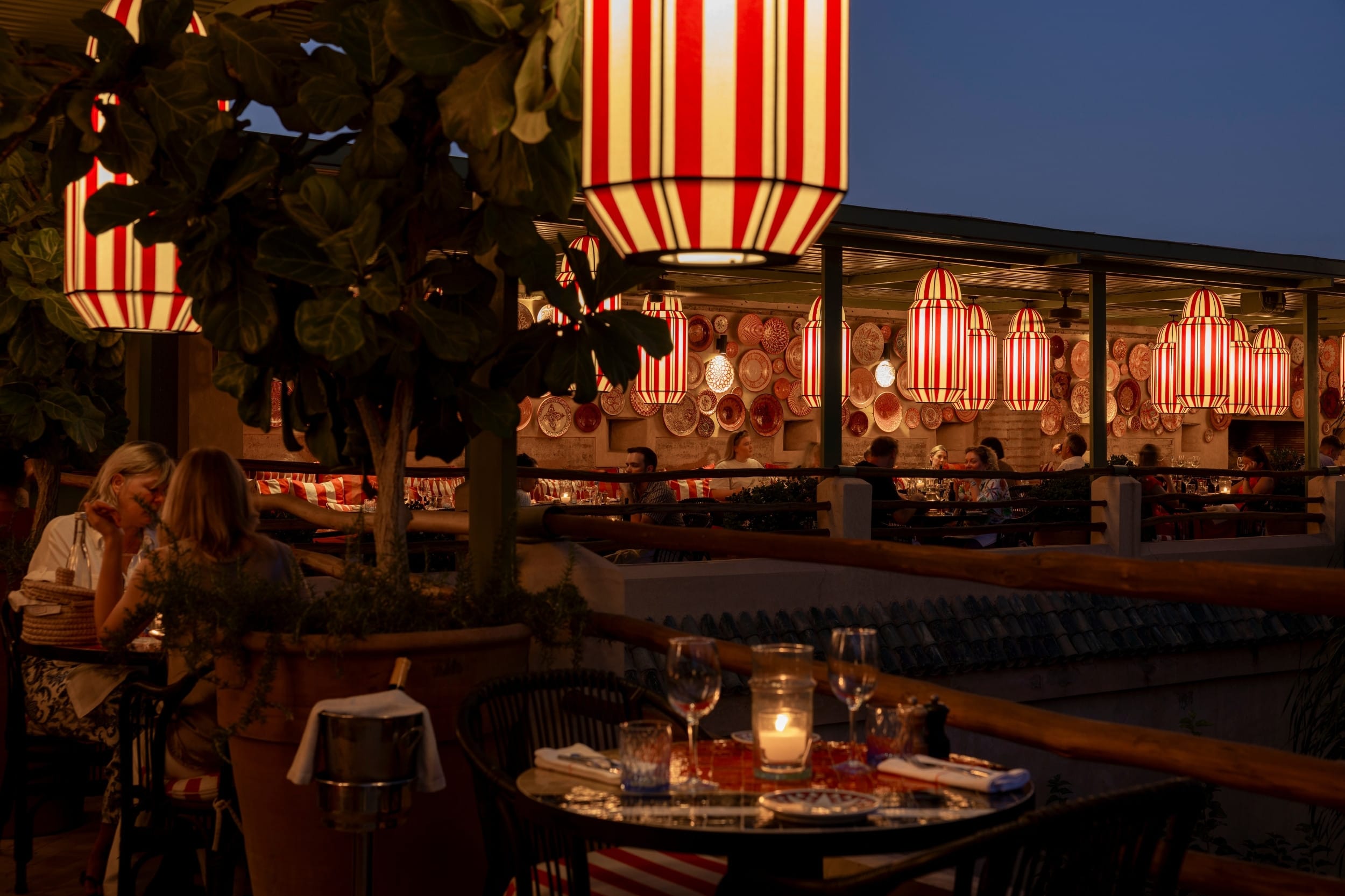 The rooftop restaurant at dusk, lit by red-and-white striped lanterns