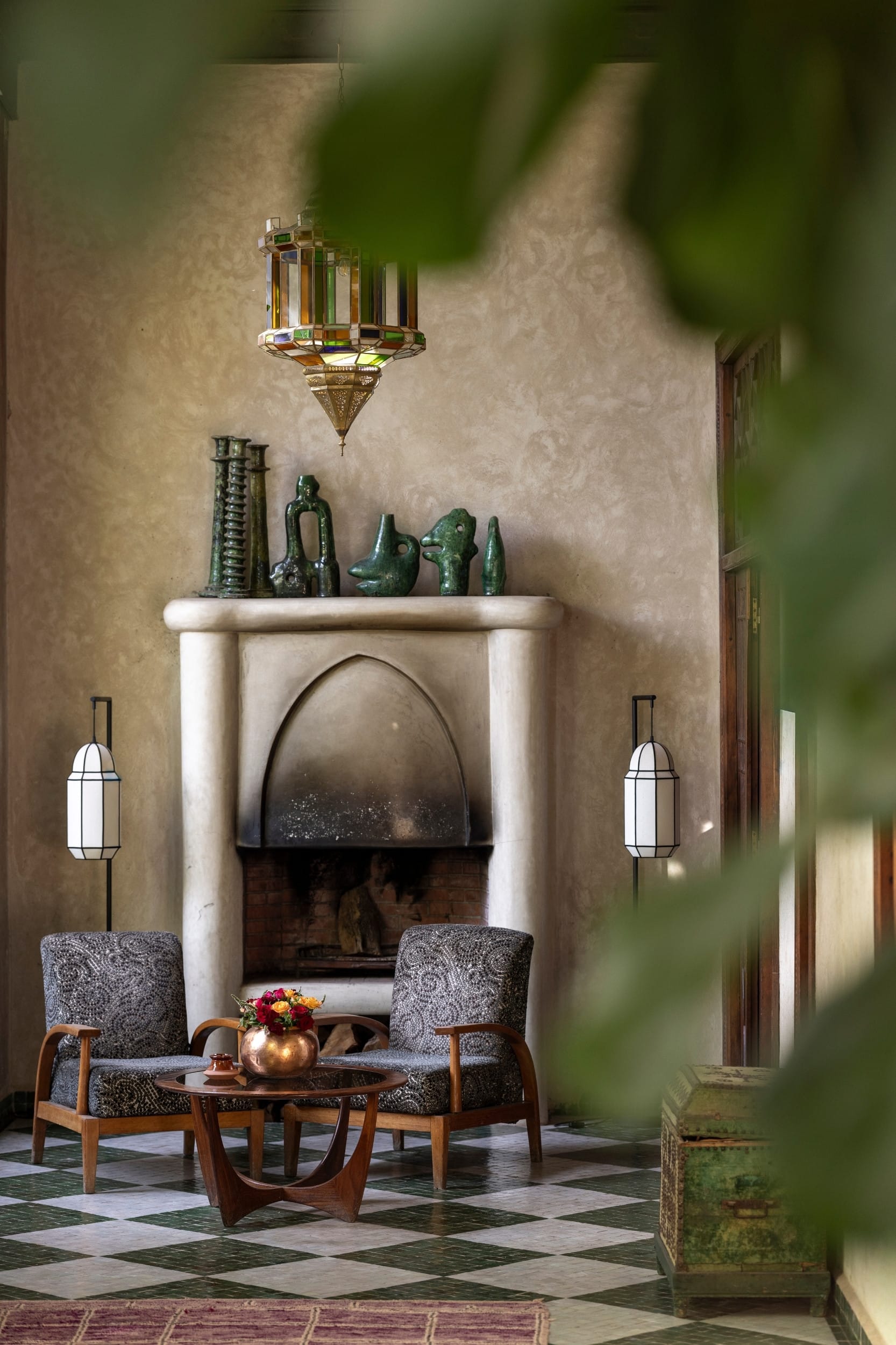 A tadelakt salon with a carved fireplace and a row of green ceramics
