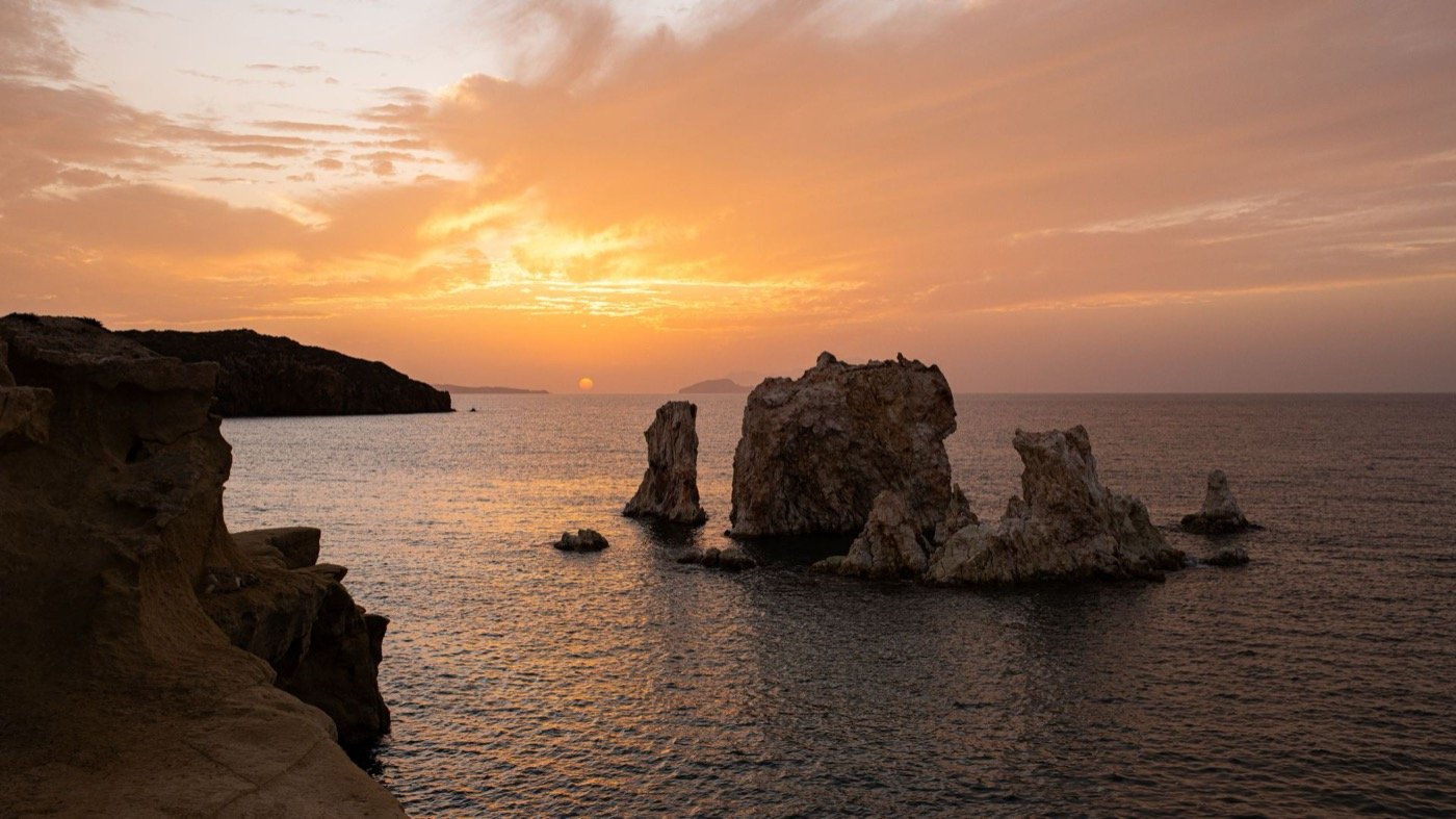 Sunset over the sea and the rock stacks off Kimolos