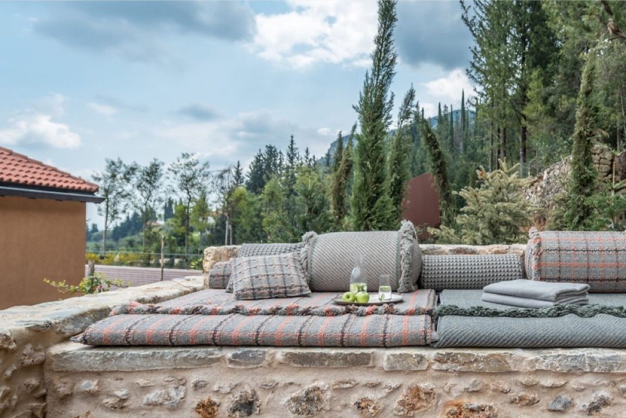 An outdoor daybed among cypresses with Mount Taygetos beyond