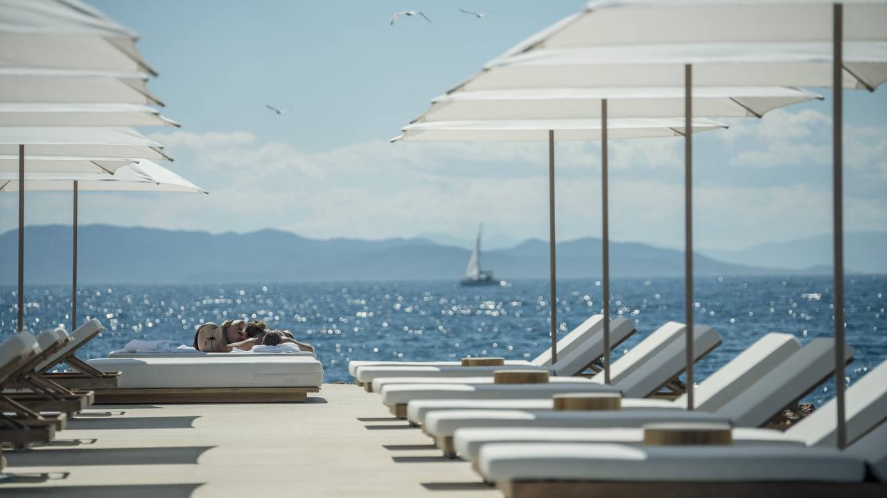Private beach loungers and umbrellas facing the Saronic Gulf