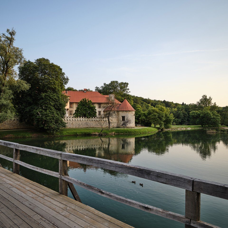 The castle seen from the wooden footbridge over the Krka, ducks on the water