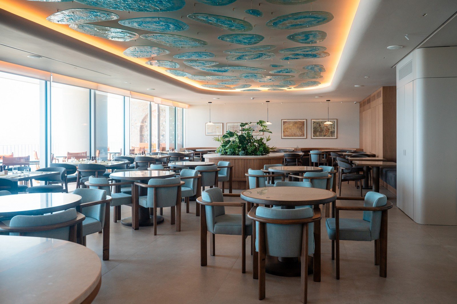 The restaurant under stone arches, tables set toward the sea