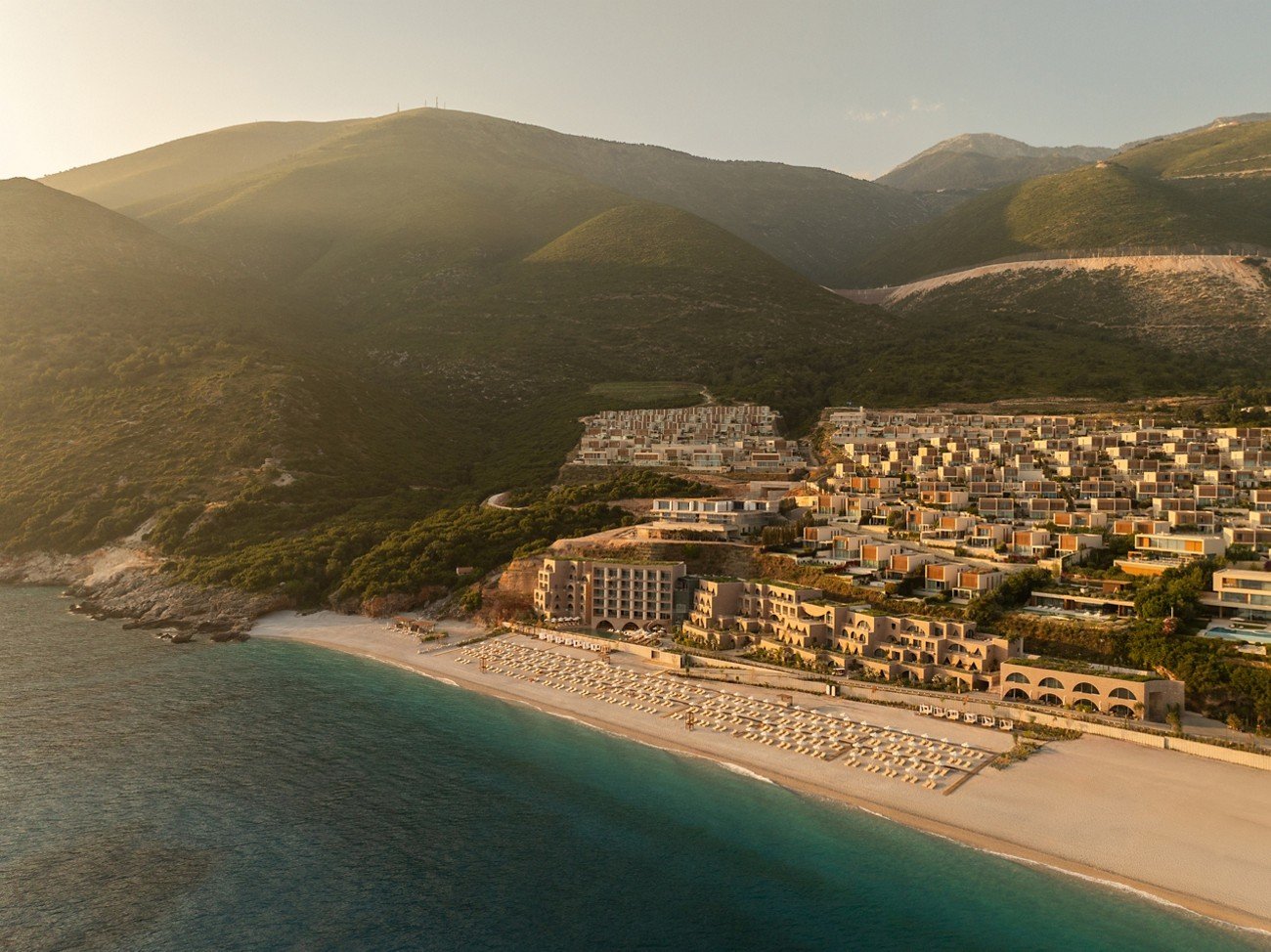 The resort set into the green hillside over a turquoise bay