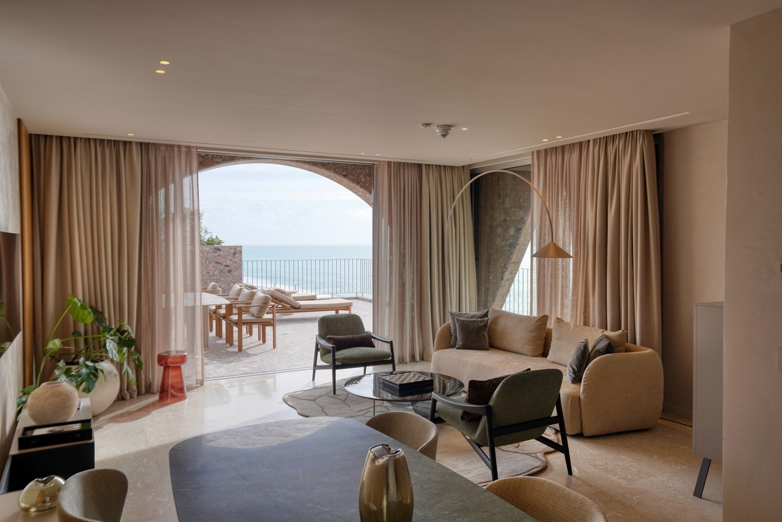 A suite living room opening through a stone arch to the sea