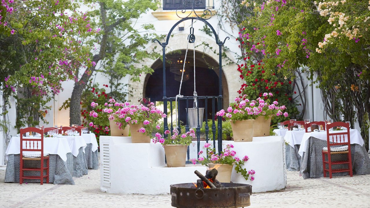 Tables laid for dinner in the courtyard among potted geraniums