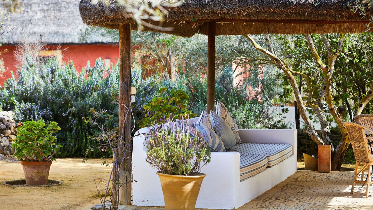 A whitewashed daybed under a thatched choza, set about with lavender